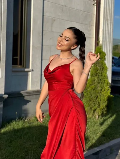 A client in a red dress with a long braided ponytail and evening makeup.