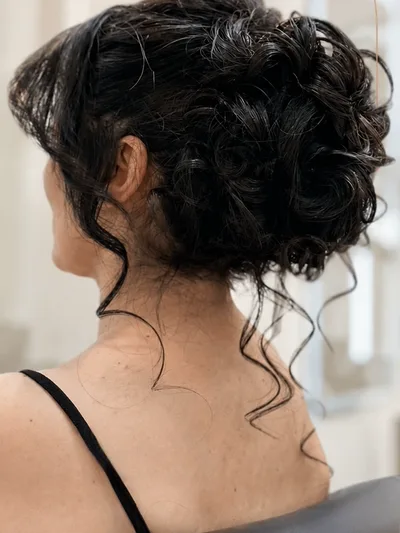 Dark curly hair pinned into a textured updo, seen from behind.