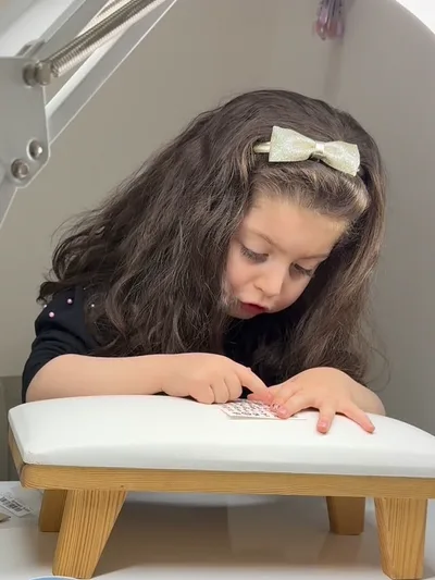 A young girl at the nail table having her nails done.