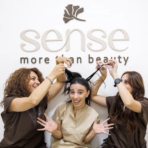 Three of the Sense team with a client under the salon's sign.